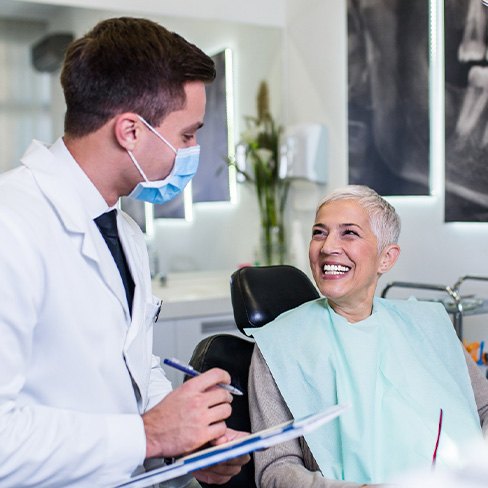 Dentist with clipboard talking to smiling patient