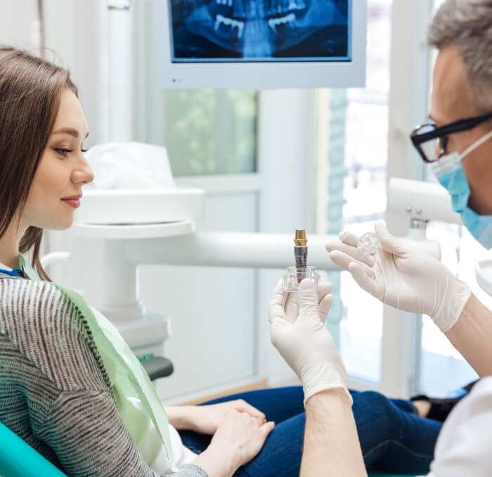 Dentist describing the dental implant process to density patient