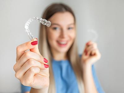 Woman with red nails holding Invisalign