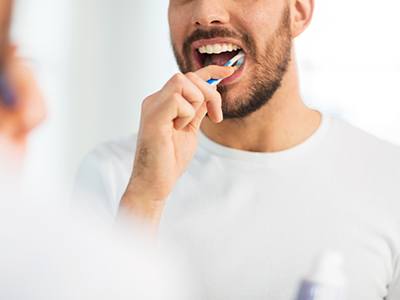 Man in white t-shirt brushing teeth
