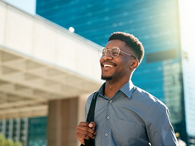 Man in glasses walking in city sunlight