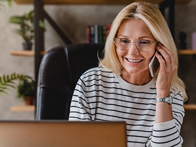 Woman with glasses smiling while talking on phone