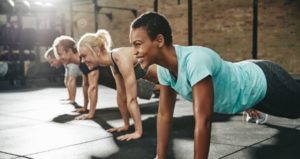 Group of people smiling while exercising at the gym.