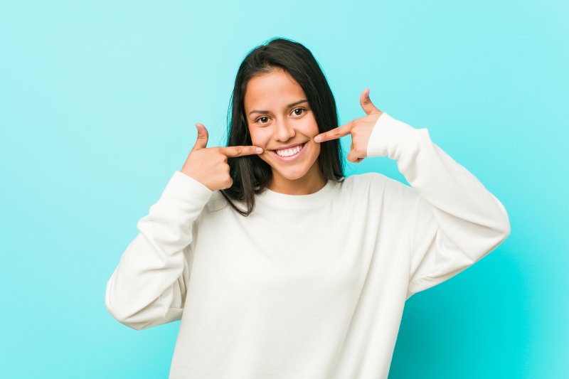 young girl pointing to white smile 