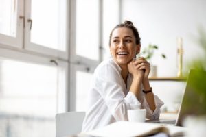 a young woman smiling while sitting at a desk

