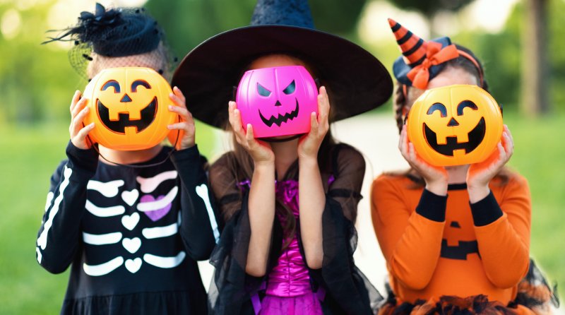 Some kids in their Halloween costumes with jack o' lantern smiles