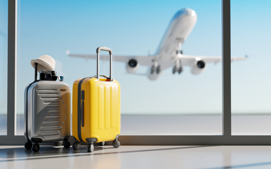 Suitcases overlooking an airport window while a plane takes off