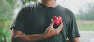 Man holding red heart over his chest.